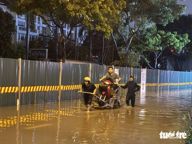 Heavy rains flood Hanoi streets again, residents struggle to get home - Ảnh 4.