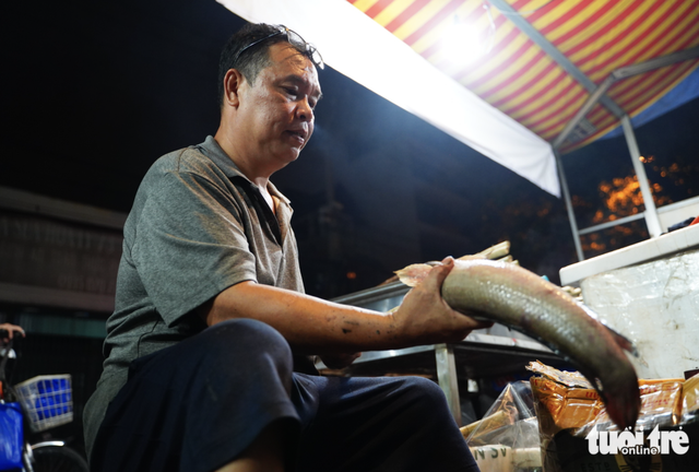 Charcoal burns overnight as vendors prepare grilled snakehead fish for God of Wealth Day in Ho Chi Minh City- Ảnh 1.