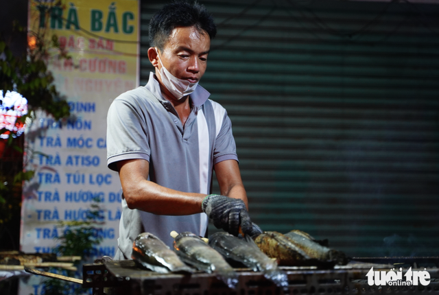 Charcoal burns overnight as vendors prepare grilled snakehead fish for God of Wealth Day in Ho Chi Minh City- Ảnh 4.