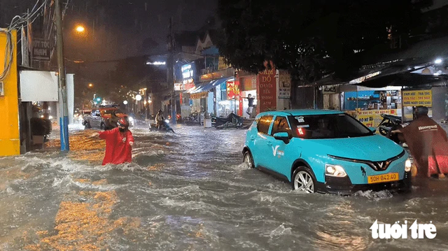 Heavy rain turns streets into torrents, knocks motorcyclists down in Ho Chi Minh City - Ảnh 1.