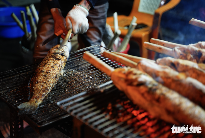 Charcoal burns overnight as vendors prepare grilled snakehead fish for God of Wealth Day in Ho Chi Minh City- Ảnh 6.