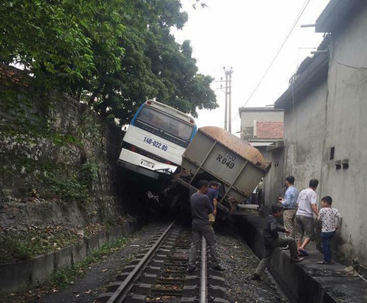 Va chạm xe lửa chở than, xe khách lơ lửng giữa kè đá - Ảnh 1.