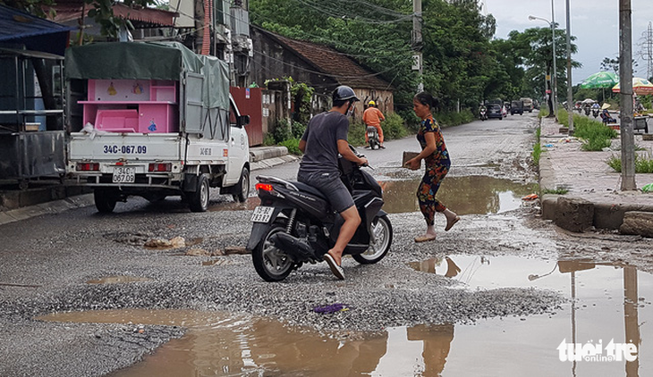 Đường 14 tỉ phập phều như bánh tráng, dân mang đá ra vá - Ảnh 1.