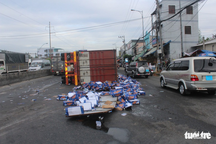 Xe container chở bia lật ngang, dân giúp tài xế gom bia - Ảnh 1.