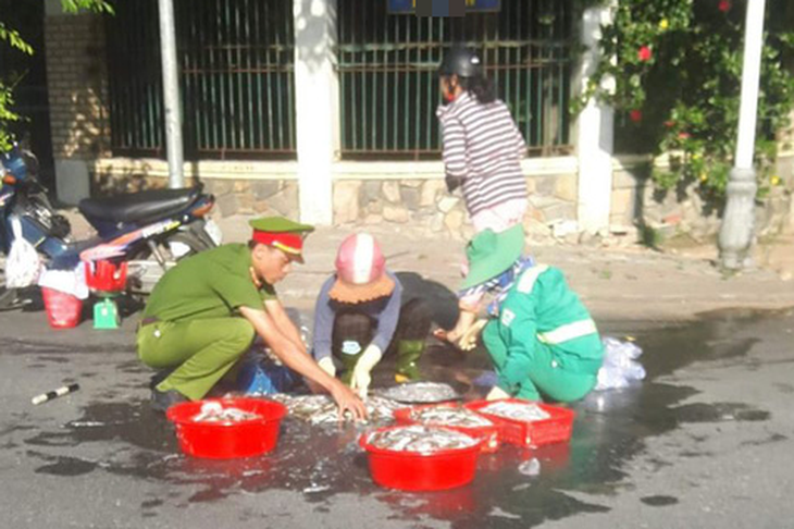 Dễ thương anh công an, chị lao công giúp dân lượm hết mớ cá đổ trên đường - Ảnh 1.