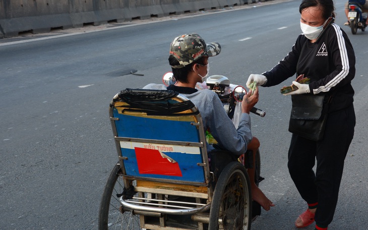 Người phụ nữ mang dép lê đi phát tiền giúp người về quê