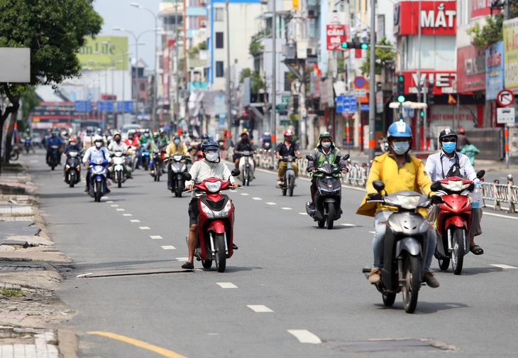 Gần trưa, đường phố TP.HCM vẫn đông người đi lại - Ảnh 1.