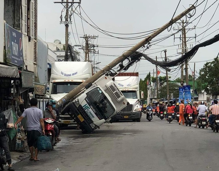 Trụ điện ngã đè trúng xe tải, nghi bị xe container quẹt cuốn bó cáp viễn thông - Ảnh 1.