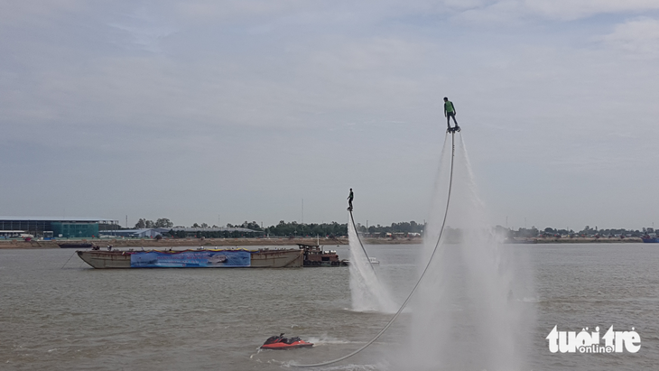 Người dân chen kín bờ kè sông Tiền xem flyboard, dù lượn - Ảnh 1.