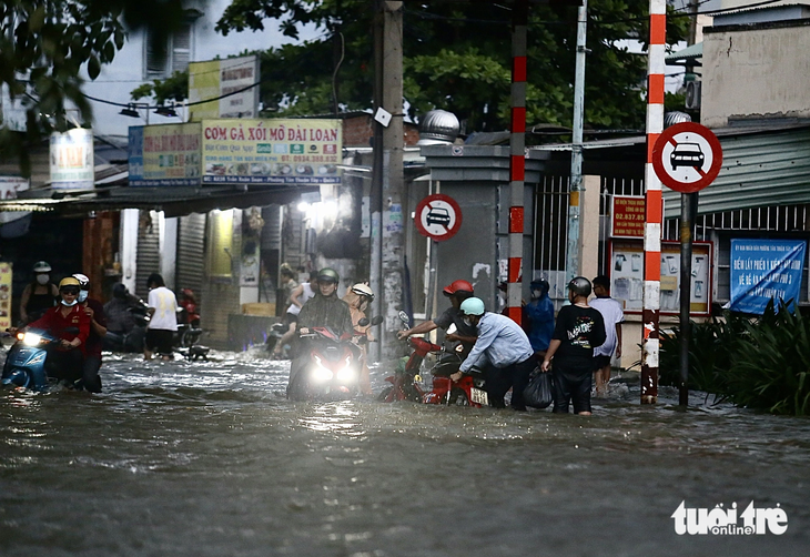 Người dân trên đường Trần Xuân Soạn hỗ trợ người đi đường bị té ngã do triều cường