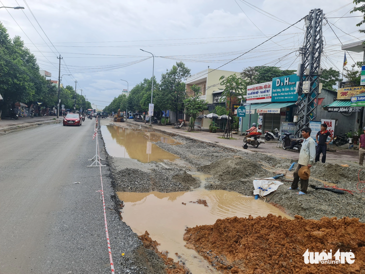 Nhà thầu thay vì thi công phải bố trí người hút nước mưa đọng trên mặt đường - Ảnh: TRẦN MAI