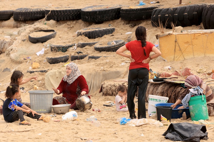 Một phụ nữ Palestine rửa nồi nấu ăn bằng nước biển do thiếu nước ngọt và điện, dọc theo bãi biển ở Deir el-Balah, phía Nam Dải Gaza, ngày 29-10 - Ảnh: AFP