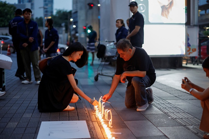 Du khách thắp nến bên ngoài trung tâm thương mại Siam Paragon ngày 4-10 - Ảnh: REUTERS