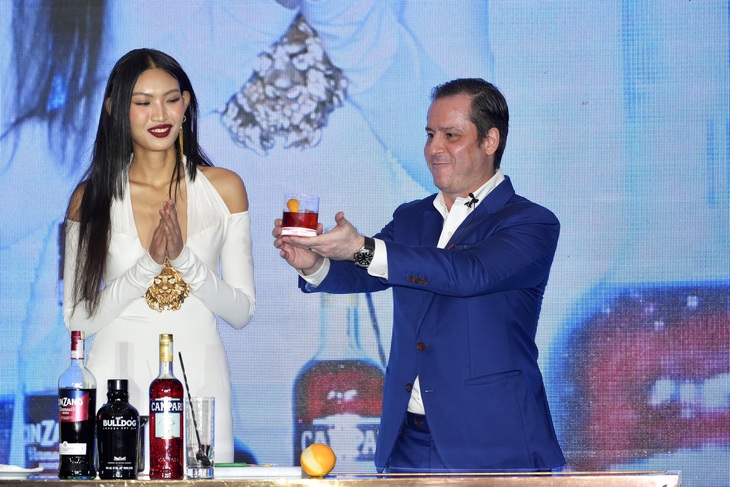 Quán quân The Face Vietnam 2023 Huỳnh Tú Anh (trái) hỗ trợ thực hiện món cocktail Negroni nổi tiếng của Ý. Negroni được pha từ các phần bằng nhau của gin, vermouth rosso và campari, thường được trang trí bằng một lát cam hoặc vỏ cam. Negroni được coi là một loại rượu khai vị - Ảnh: HỮU HẠNH