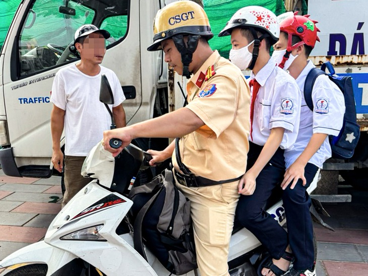 Cảnh sát giao thông đưa 2 nam sinh đến trường sau khi lập biên bản xử lý vi phạm nồng độ cồn - Ảnh: H.Q.