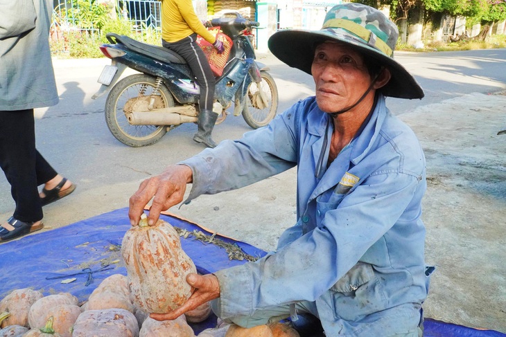 Ông Hoàng Công Nhật chỉ tay vào trái bí đỏ đã bị hư khi thu hoạch đã lâu mà không tiêu thụ được 