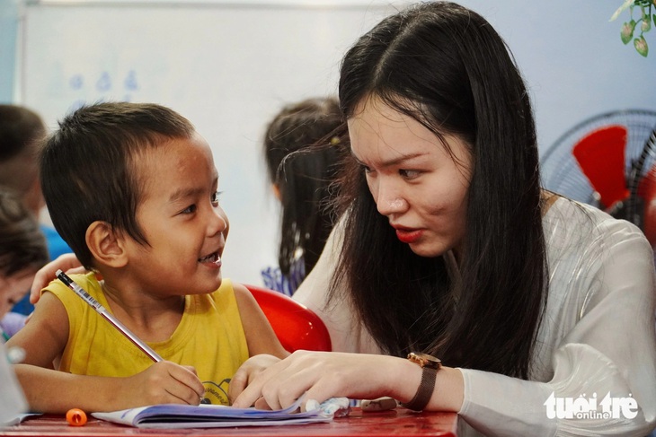 Một tình nguyện viên giúp các em học mẫu giáo làm quen với mặt chữ - Ảnh: TRẦN HOÀI