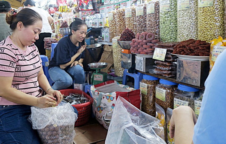 Bà Bảo Trân (phải), tiểu thương sạp mứt kẹo Ngọc Châu tại chợ Bến Thành, cho biết có một số đơn ảo, nên bán không nhiều như đã chốt đơn lúc đầu - Ảnh: T.T.D.