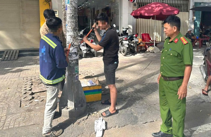 Ba người đang làm sạch một trụ điện trên đường Trần Hưng Đạo (quận 5) - Ảnh: A.X.