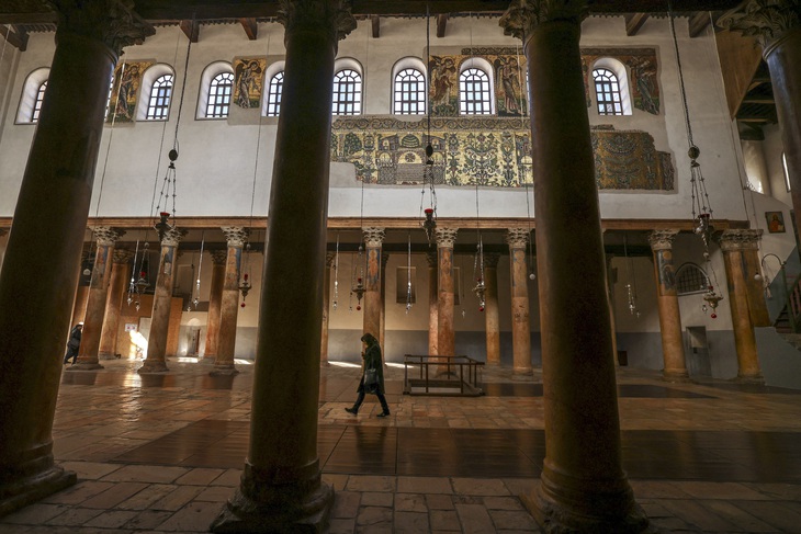 Một người bước đi lặng lẽ trong nhà thờ Giáng sinh ở Bethlehem ngày 20-12 - Ảnh: AFP