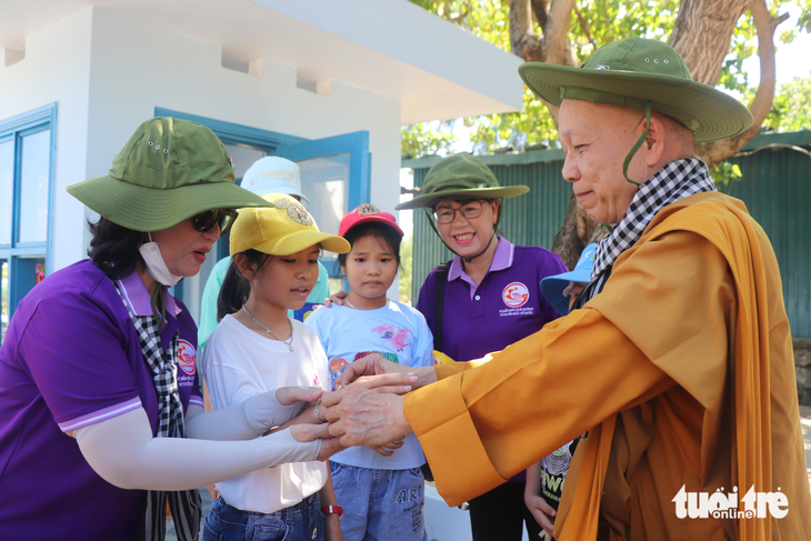 Mang những xâu chuỗi đầy ắp các túi, thầy Thích Minh Thành - Phó viện trưởng Viện nghiên cứu Phật học Việt Nam - đeo tận tay những đứa trẻ con của ngư dân trên các đảo, với mong muốn gửi gắm những bình an nơi &quot;đầu sóng ngọn gió&quot; - Ảnh: CẨM NƯƠNG