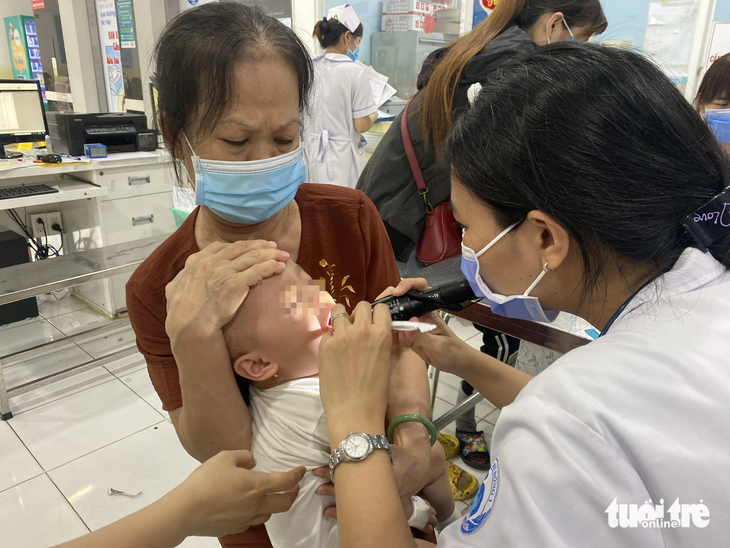 Bác sĩ thăm khám vết loét trong miệng bệnh nhi mắc tay chân miệng đang điều trị tại khoa nhiễm - thần kinh Bệnh viện Nhi đồng 1 (TP.HCM) - Ảnh: X.MAI