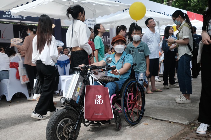 Chị Bùi Thị Hương (Hà Đông, Hà Nội) ngồi xe lăn, vượt hơn 10 cây số đến Đại học Bách Khoa Hà Nội cùng con, học lớp 11, nghe tư vấn. &quot;Con muốn học Đại học Kiến trúc nên gia đình cũng đã cho cháu đi học vẽ. Điều tôi quan tâm là việc học các trường này có gắn liền với thực hành nhiều không, cũng như cơ hội việc làm sau này ra sao. Cháu đam mê nhưng đam mê của cháu cũng cần gắn với thực tế&quot;, chị Hương cho biết - Ảnh: MAI THƯƠNG