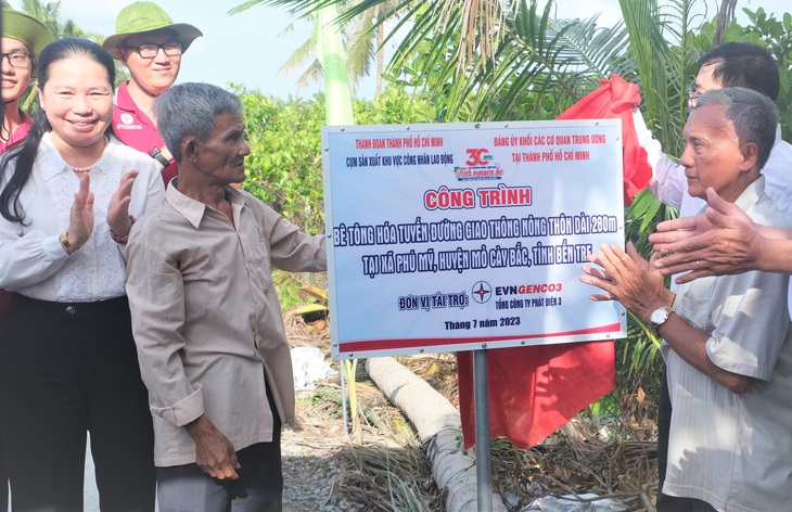 Bà con địa phương được mời gỡ băng khánh thành và nhận bàn giao con đường liên ấp được bê tông hóa tại xã Phú Mỹ (huyện Mỏ Cày Bắc, Bến Tre) - Ảnh: Q.L.