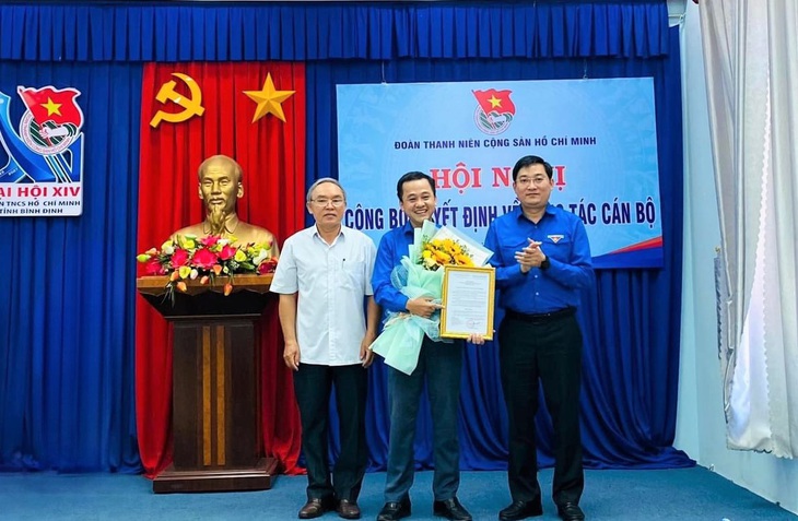 Anh Bùi Minh Tuấn (bên phải) trao quyết định công nhận chức danh bí thư Tỉnh Đoàn và tặng hoa chúc mừng anh Nguyễn Thành Trung - Ảnh: N.Đ.