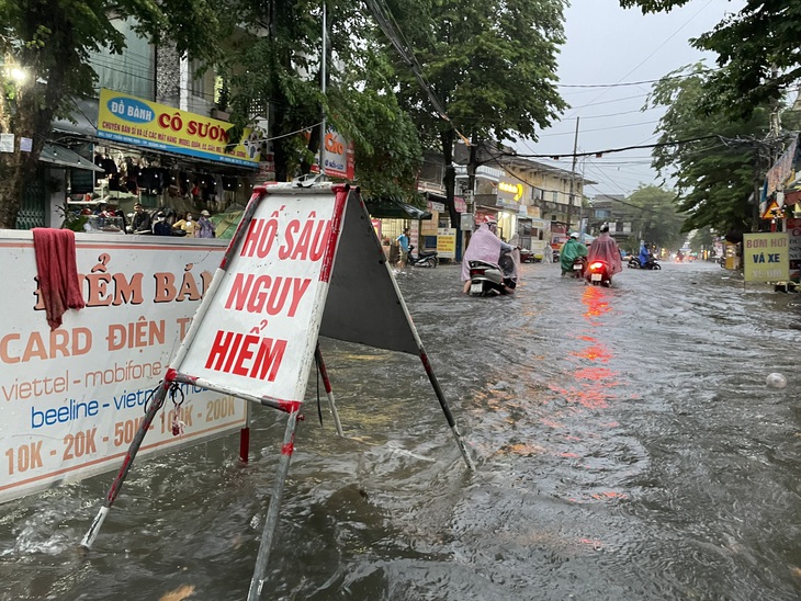 Cơ quan chức năng phải lắp biển &quot;hố sâu nguy hiểm&quot; để bật nắp cống nhằm giúp thoát nước nhanh hơn - Ảnh: T.M