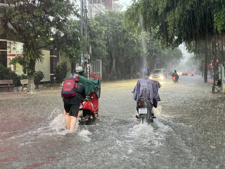 Một phụ huynh đón con về, đành phải dắt bộ bì xe ngập nước chết máy - Ảnh: T.M