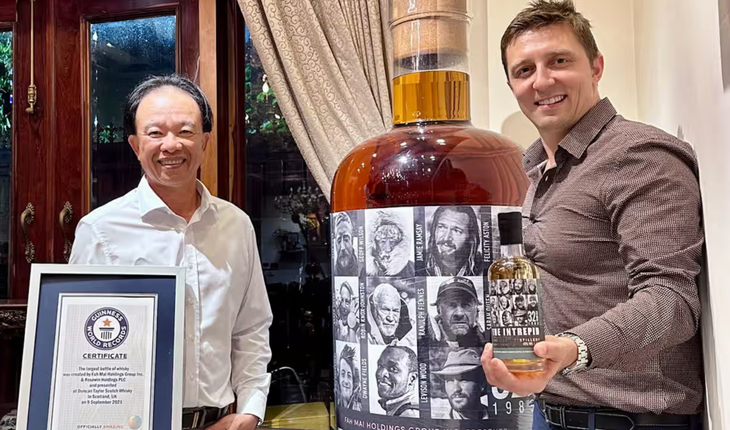 Ông Nguyễn Đình Tuấn Việt và ông Daniel Monk bên cạnh chai rượu whisky lớn nhất thế giới - Ảnh: PA