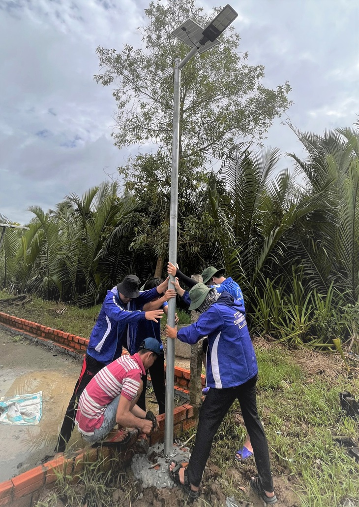 Chiến sĩ tình nguyện Mùa hè xanh Trường đại học Kinh tế - Luật (Đại học Quốc gia TP.HCM) cùng bà con làm công trình &quot;Thắp sáng đường quê&quot; chiếu sáng bằng đèn sử dụng năng lượng mặt trời - Ảnh: Q.L.