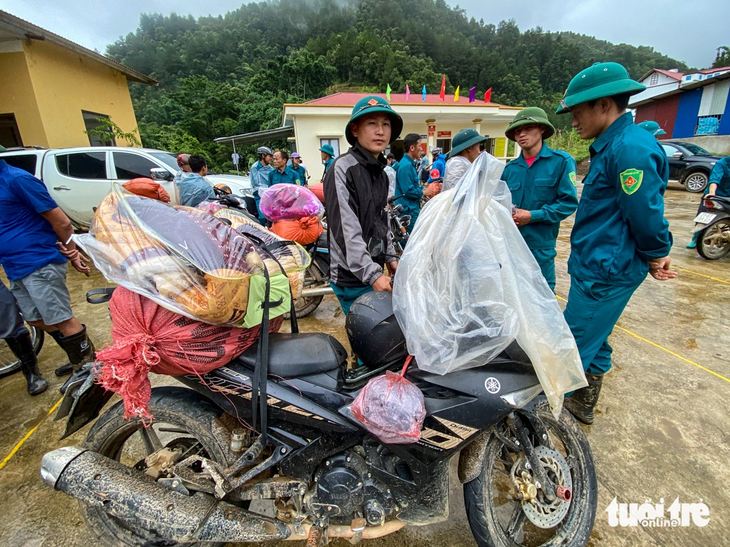 Do nhiều nơi vẫn ngập sâu trong bùn đất, lực lượng chức năng phải dùng xe máy chở theo chăn màn, gạo, bánh mì, mì gói, nước sạch cho bà con - Ảnh: CHÍ TUỆ