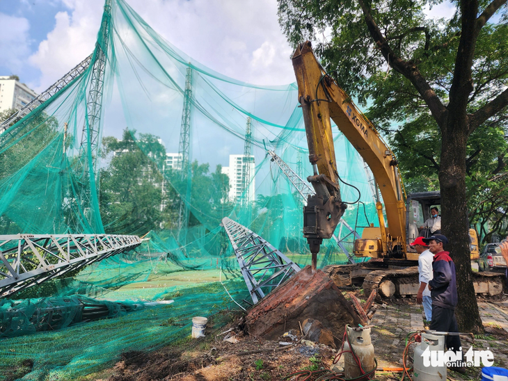 Các nhân công tháo dỡ trụ sắt bị gió mạnh quật ngã - Ảnh: NGỌC KHẢI