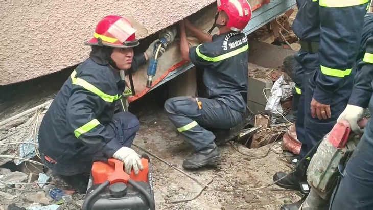 Lực lượng cứu nạn cứu hộ đang khẩn trương dùng máy thủy lực, nâng mảng bê tông cứu người còn lại - Ảnh: PC07