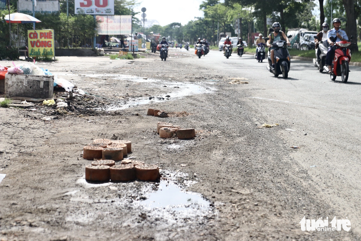 Có những đoạn người dân dùng gạch đá, than tổ ong lấp tạm điểm trũng để cảnh báo người đi đường không đi vào - Ảnh: TIẾN QUỐC