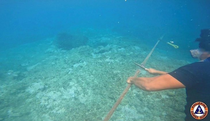 Thành viên Lực lượng tuần duyên Philippines lặn cắt đoạn phao nổi gần bãi cạn Scarborough - Ảnh: REUTERS