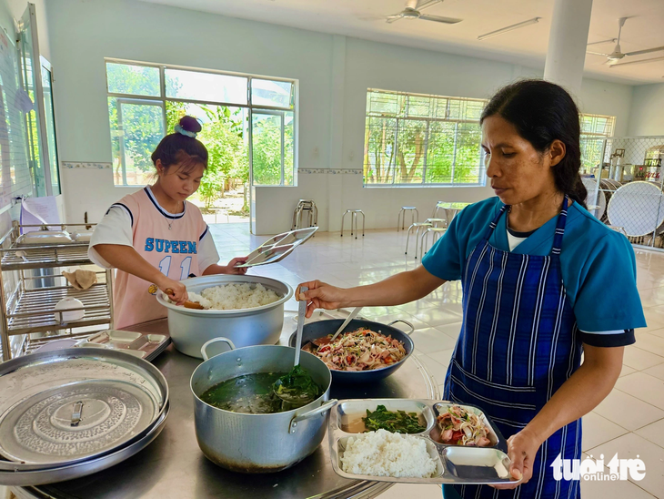 Bạn Cao Thị Kim Mỹ phụ phát cơm cho nhiều người ở Trung tâm Bảo trợ xã hội huyện Khánh Sơn - Ảnh: MINH CHIẾN