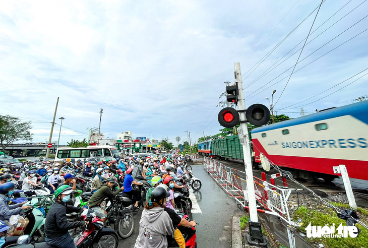 Người dân dừng chờ tàu chạy ngang tại đường sắt khu vực TP Thủ Đức - Ảnh: LÊ PHAN