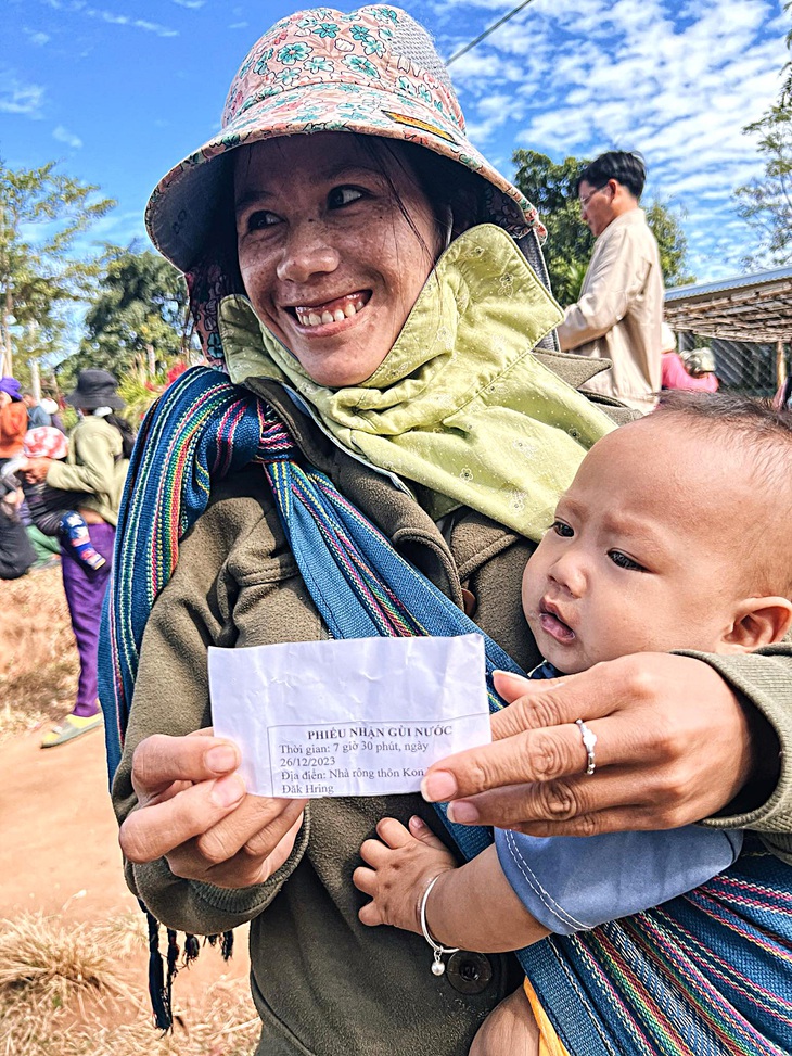 Một phụ nữ trẻ ở thôn Kon Mong (huyện Đăk Hà) địu con đi nhận gùi nước mới