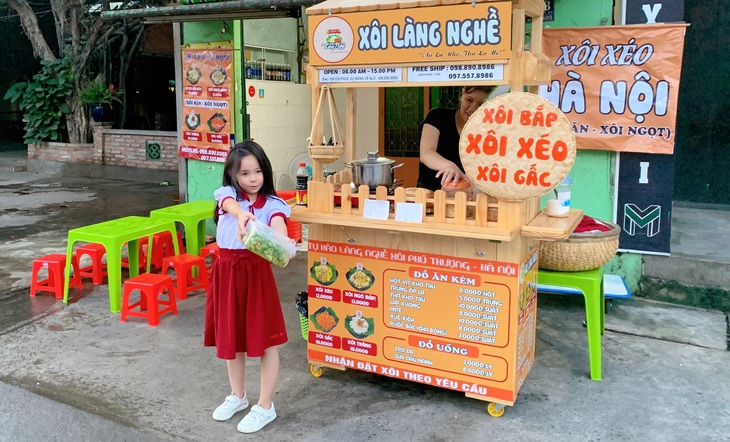 Con gái của anh Long đứng cạnh chiếc xe đẩy xôi trên vỉa hè lúc vợ chồng anh mới lập nghiệp - Ảnh: NVCC