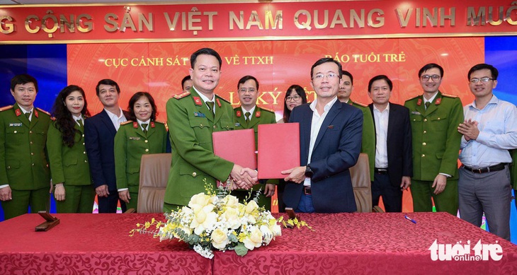 Phó cục trưởng Cục C06 - Bộ Công an Vũ Văn Tấn và Phó tổng biên tập báo Tuổi Trẻ Trần Xuân Toàn trao đổi văn bản ký hợp tác - Ảnh: NAM TRẦN