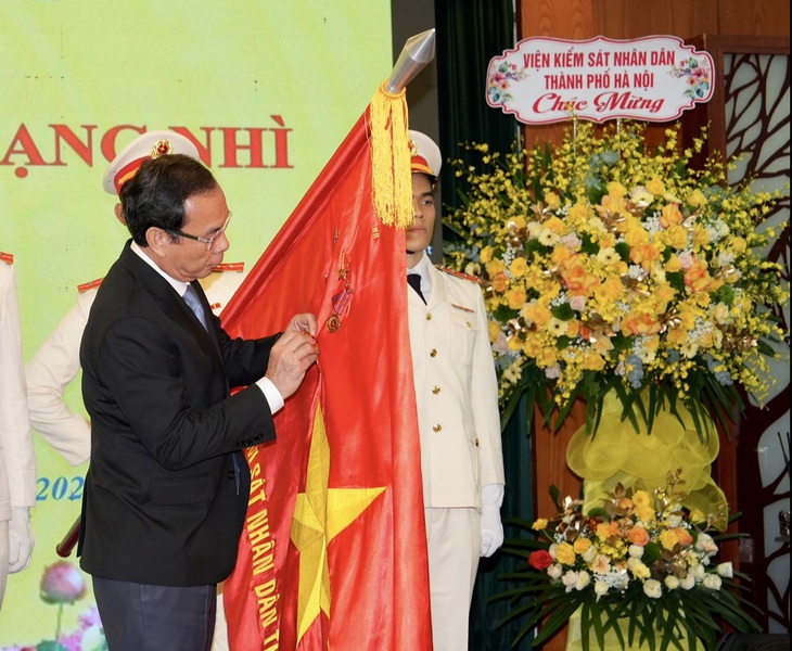 Bí thư Thành ủy Nguyễn Văn Nên gắn huân chương lên cờ truyền thống - Ảnh: HỮU HẠNH