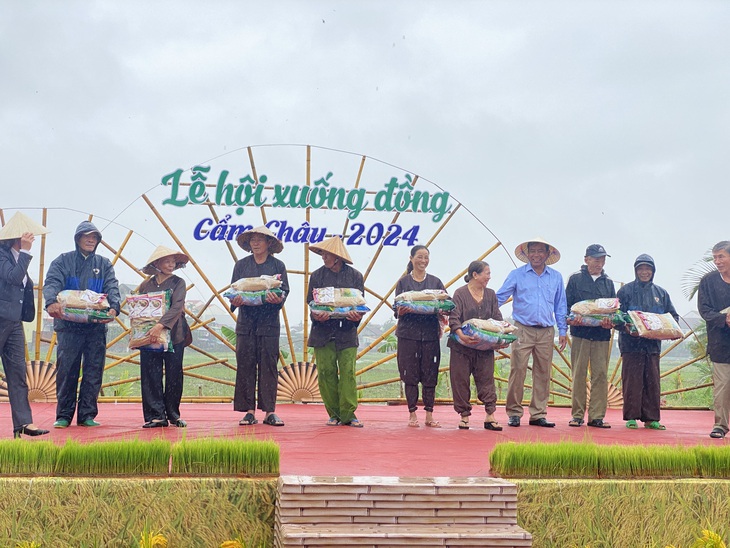 Nông dân được mời lên sân khấu để tặng lúa giống, phân bón hữu cơ trong lễ hội xuống đồng đầu năm - Ảnh: B.D.