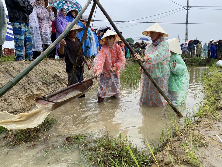 Khách nước ngoài lội xuống mương tát nước, tập làm nông dân - Ảnh: B.D.