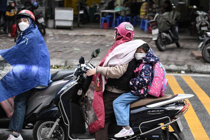 Học sinh Trường tiểu học Nguyễn Du (quận Nam Từ Liêm, Hà Nội) được bố mẹ đưa đến trường sáng 23-1, mặc dù nhà trường thông báo học sinh được nghỉ học - Ảnh: NAM TRẦN