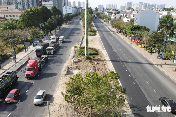 Hai làn xe mới sát tiểu đảo cây xanh trên đường Đồng Văn Cống đã hoàn thiện, nổi bật lên bởi màu nhựa mới - Ảnh: PHƯƠNG NHI