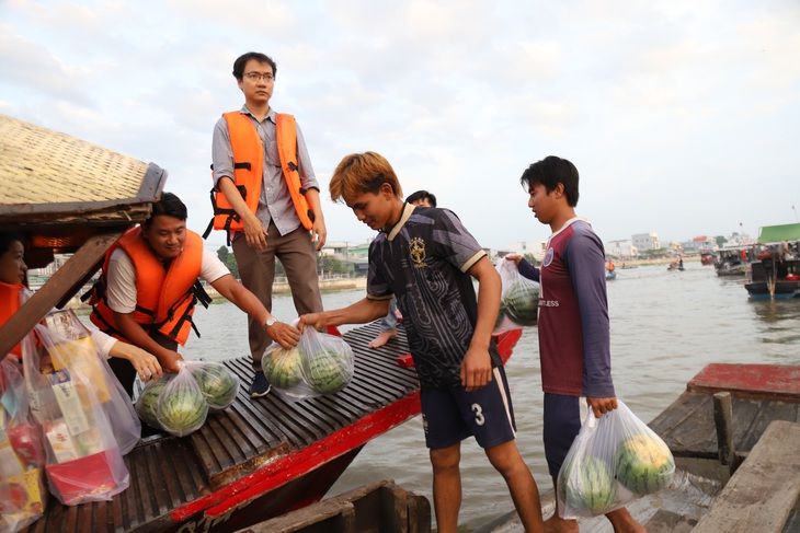 Đoàn trao quà cũng mua nhiều dưa hấu của thương hồ để ủng hộ, động viên bà con trong hoạt động buôn bán những ngày cận Tết - Ảnh: CHÍ QUỐC