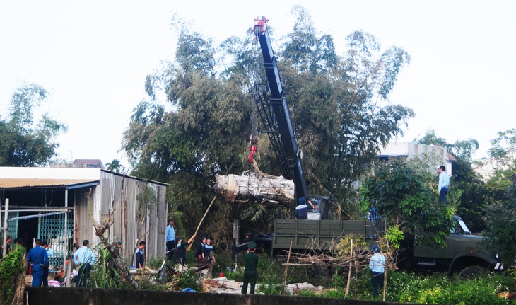 Máy cẩu đưa khối động cơ lên xe tải rời khỏi hiện trường nơi máy bay rơi - Ảnh: B.D.